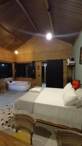 a bedroom with a large bed and a bath tub at REFUGIO PIEMONTE Chalés in Socorro