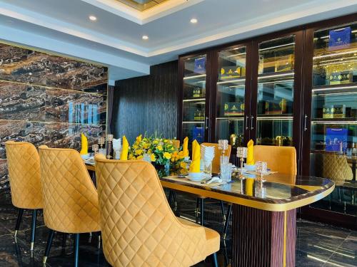 a dining room with a table and yellow chairs at Sandals Lily Hotel in Da Lat