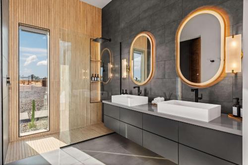 a bathroom with two sinks and two mirrors at Pool-Spa -DayBeds- Firepit-Golf in Joshua Tree