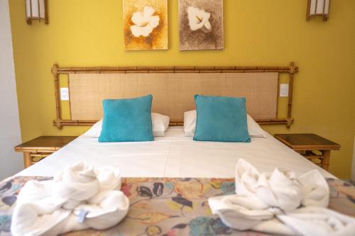 a bedroom with a bed with blue pillows and towels at Pousada Sol e Mar in Juquei