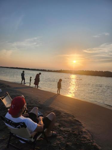 a man sitting in a chair on the beach watching the sunset at ロッヂノエル in Seki