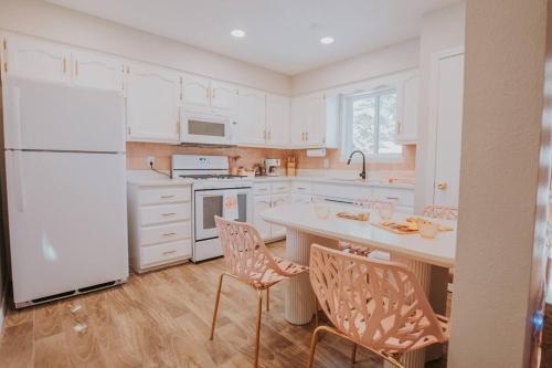 a kitchen with a white refrigerator and a table and chairs at 50 Shades of Pink-Private Hot Tub! in Albuquerque