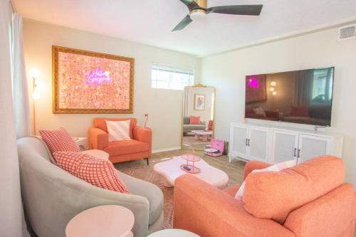 a living room with orange furniture and a flat screen tv at 50 Shades of Pink-Private Hot Tub! in Albuquerque