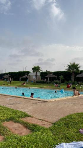 Appartement avec piscine à casa tamaris في دار بوعزة: مجموعة من الأشخاص في حمام السباحة