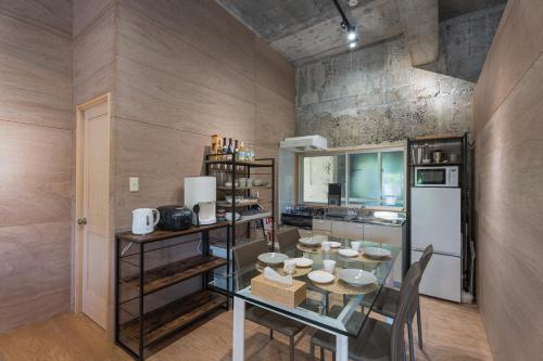 a kitchen with a glass table and a refrigerator at ダイバーズヴィラYoNNER in Aguni