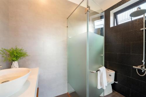 a bathroom with a glass shower and a sink at U Maison by Class6 in Hoi An