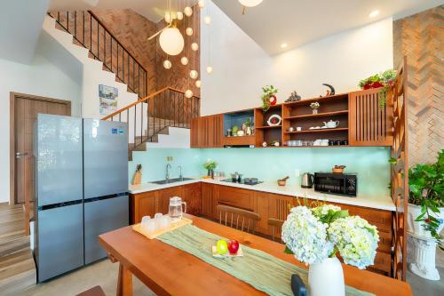 a kitchen with a wooden table and a refrigerator at U Maison by Class6 in Hoi An