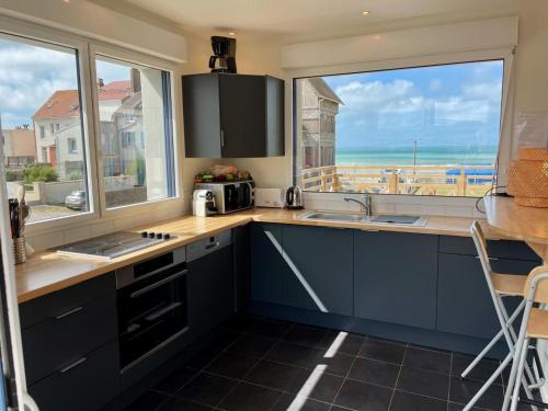 a kitchen with blue cabinets and a view of the ocean at Duplex élégant 3 chambres avec terrasses, draps fournis, WiFi, jardin, à Ambleteuse - FR-1-376-9 in Ambleteuse