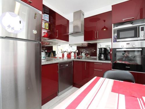 La cuisine est équipée de placards rouges et d'un réfrigérateur en acier inoxydable. dans l'établissement T2 moderne à Balaruc-les-Bains avec clim, parking et wifi - FR-1-553-271, à Balaruc-les-Bains