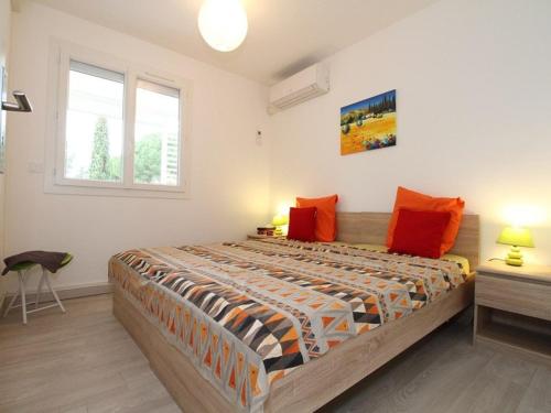 a bedroom with a large bed with orange pillows at T2 moderne à Balaruc-les-Bains avec clim, parking et wifi - FR-1-553-271 in Balaruc-les-Bains