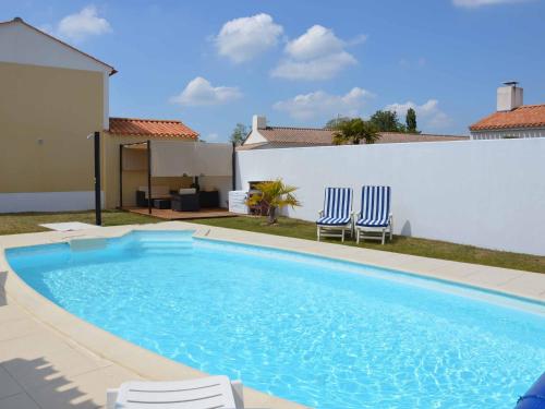 une piscine avec deux chaises et une maison dans l'établissement Villa calme avec piscine privée, animaux admis, WiFi - FR-1-323-552, à Saint-Jean-de-Monts