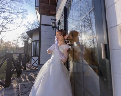 a young girl in a wedding dress standing in front of a window at カナリアンホテル in Tateshina