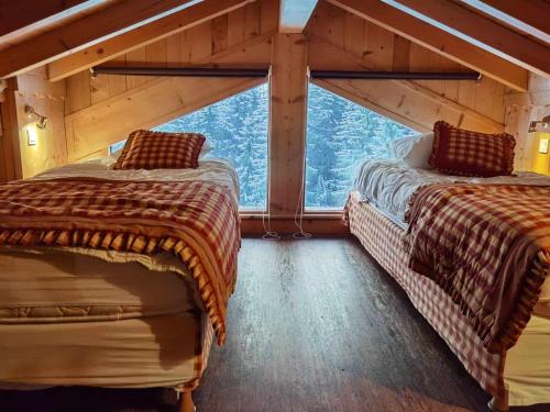 deux lits dans une chambre avec une grande fenêtre dans l'établissement Superbe chalet 15 pers. avec spa, sauna, proche télécabine et centre, équipements complets - FR-1-679-17, à Morzine