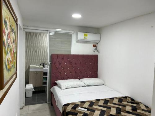 a small bedroom with a bed with a red headboard at Habitaciones villa oti in Ciénaga