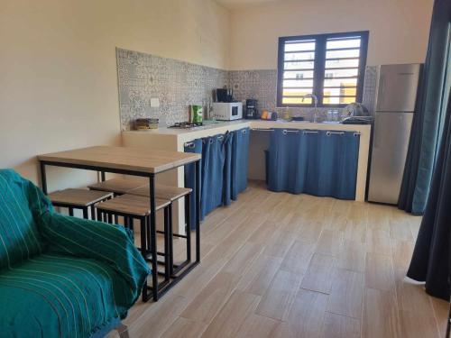a kitchen with a table and a kitchen with blue curtains at Ti kaz Palmiste in Saint-Philippe