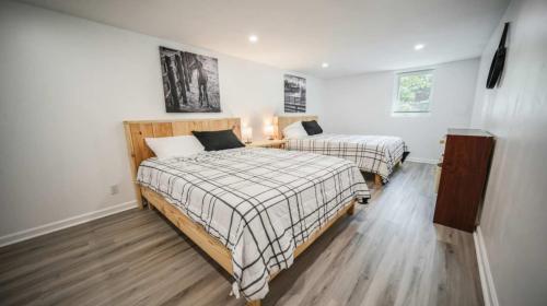 two beds in a room with white walls and wood floors at Spacious 2-BR Retreat Near Louisville Attractions in Louisville