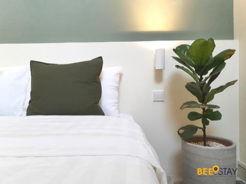 a bedroom with a bed with a green pillow and a plant at Jenjarom No 32 Modern Cozy Homestay for 4 Pax by Beestay in Jenjarum