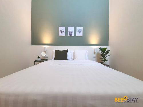 a bedroom with a large white bed with two pictures on the wall at Jenjarom No 32 Modern Cozy Homestay for 4 Pax by Beestay in Jenjarum