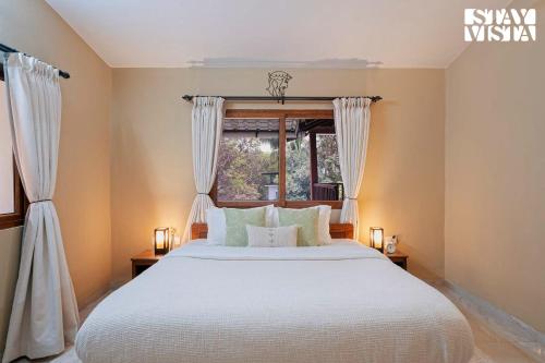 a bedroom with a white bed and a window at StayVista at Casa Chalora with Pool, BBQ, Games Room in Candolim