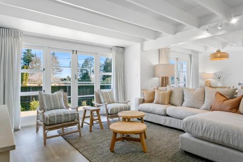 a living room with a couch and chairs and windows at The Quarters in Turangi
