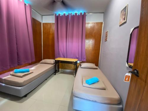 two beds in a room with purple curtains at I-go Homestay Subang Airport in Shah Alam