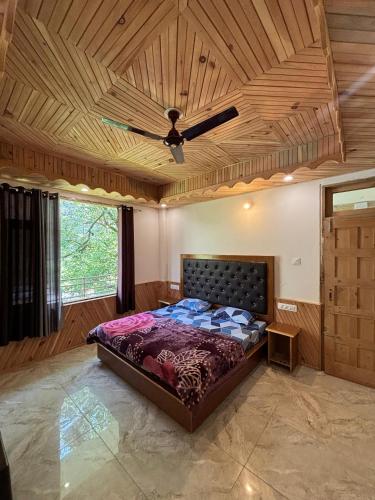 a bedroom with a large bed with a ceiling at Pine view kasol in Kasol