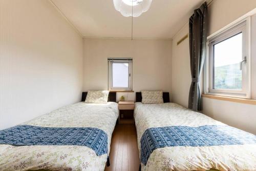 two beds in a room with two windows at Warabe in Otaru