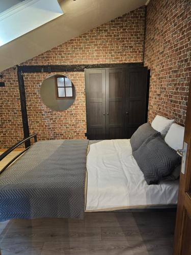 a bedroom with a large bed in a brick wall at La bergerie in La Bruyère