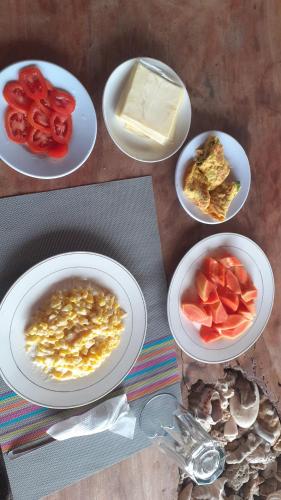 a table with plates of food with tomatoes and cheese at Tiger fish homestay in Bunaken