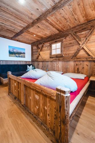 a large bed in a room with a wooden ceiling at ALMRESIDENZ UNTERRAIN - with FREE SKI BUS SHUTTLE in Valdaora