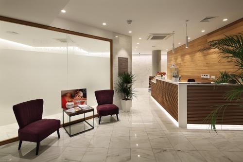 a lobby with two chairs and a table and a counter at Elysia Park Premium in Paphos City
