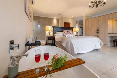 a bathroom with a bath tub with two glasses of wine at Alkantmooi Private Nature Reserve - Keurkloof & Keurbos 93 in Plettenberg Bay