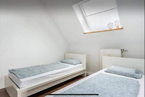 two beds in a white room with a window at Haus 6 Pers mit Garten 15 min zur Messe Düsseldorf in Krefeld