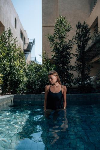 a woman is standing in a swimming pool at M Boutique Hotel - Designed for Adults in Paphos City