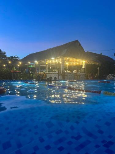 a large swimming pool at night with a tent at Khu nghỉ dưỡng sinh thái Apsara Sóc Trăng in Ấp Vĩnh Hưng