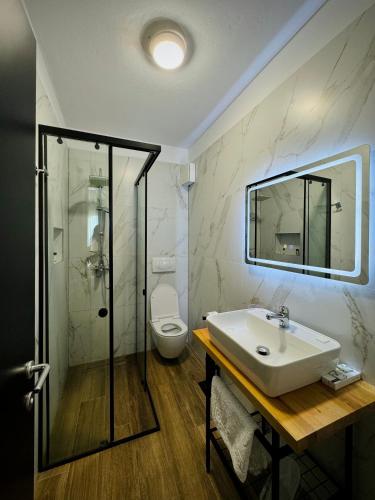 a bathroom with a sink and a shower and a toilet at Gogo's Boutique Hotel in Dhërmi