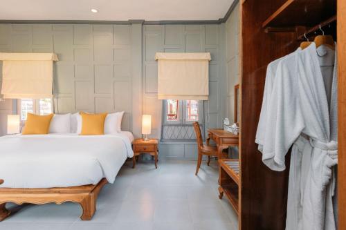 a bedroom with a bed and a desk and a room at Ma Doo Bua Stay - SHA Extra Plus in Thalang