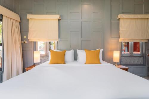 a bedroom with a large bed with yellow pillows at Ma Doo Bua Stay - SHA Extra Plus in Thalang