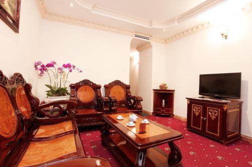 a living room with wooden furniture and a flat screen tv at New Pacific Hotel in Ho Chi Minh City