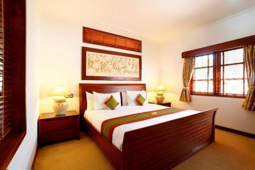 a bedroom with a large bed and two windows at Apel Villa Sanur in Sanur