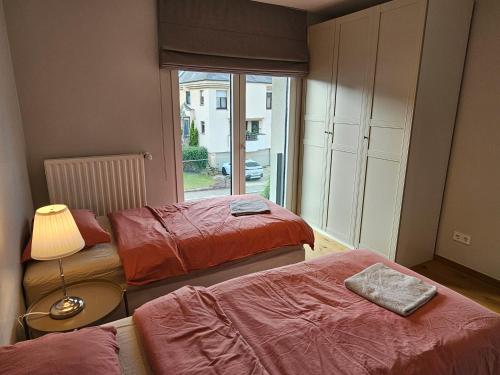 a room with three beds and a large window at Renovated 2 Bedroom Apartment with Parking & AC in Luxembourg