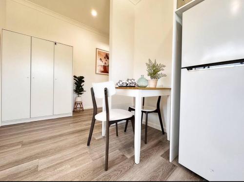 a dining room with a white table and chairs at Coastlight - Modern Beachside Studio in Woonona in Woonona