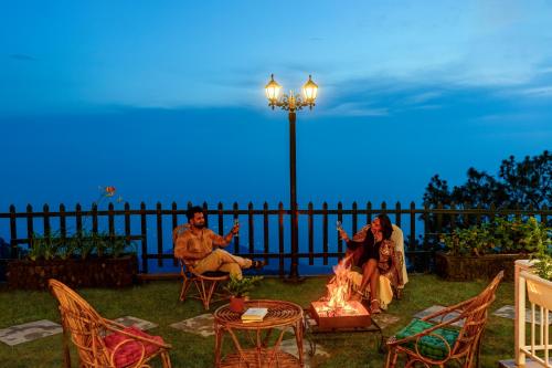 a group of people sitting around a fire at night at ELIVAAS 4 BHK With Garden & Bonfire - Fleur De Lis in Kasauli