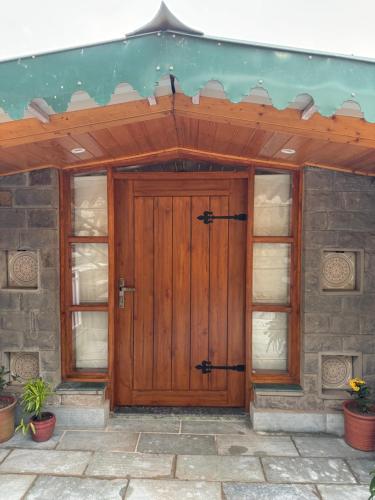 a wooden front door of a house at ELIVAAS 4 BHK With Garden & Bonfire - Fleur De Lis in Kasauli
