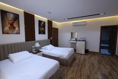 a hotel room with two beds and a refrigerator at Pyramids Sunshine View in Cairo