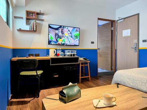 a bedroom with a desk and a tv on a wall at Journey Town Inn in Taipei