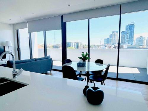 a kitchen and living room with a table and chairs at Stylish Chatswood 2BR Apartment with 3 Beds, Gym, Near Metro in Sydney