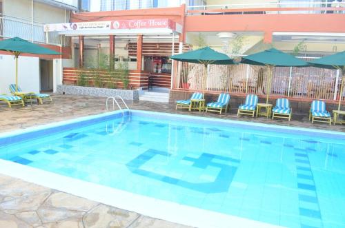 a swimming pool with chairs and umbrellas in a hotel at Golf Hotel Kakamega in Kakamega