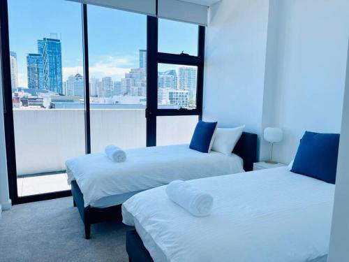 two beds in a room with a view of a city at Stylish Chatswood 2BR Apartment with 3 Beds, Gym, Near Metro in Sydney