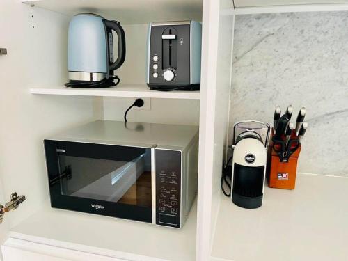 a microwave sitting on a shelf with a coffee maker at Stylish Chatswood 2BR Apartment with 3 Beds, Gym, Near Metro in Sydney